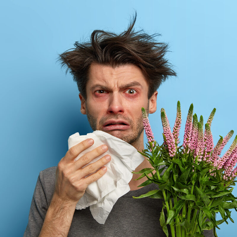 Imagen de un hombre sufriendo un brote de alergia